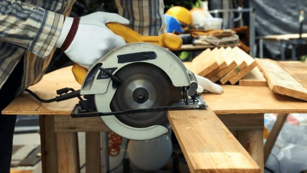 Close-up of a 5 1 2 inch circular saw making a precise bevel cut on oak wood in a sunlit workshop.