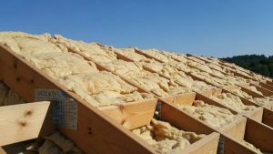 Cross-section diagram showing proper insulation installation in a box gable roof structure with ventilation baffles and air sealing details